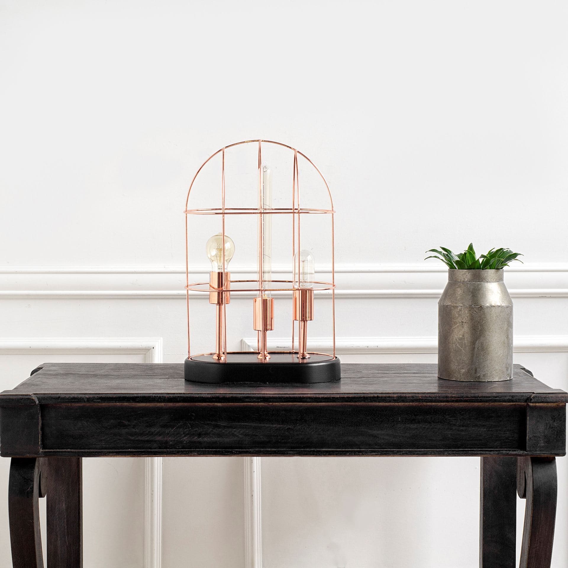 Sutton (19.3"H) Rose-Gold Metal Cylindrical Cage Three Bulb Table Lamp — in a styled room