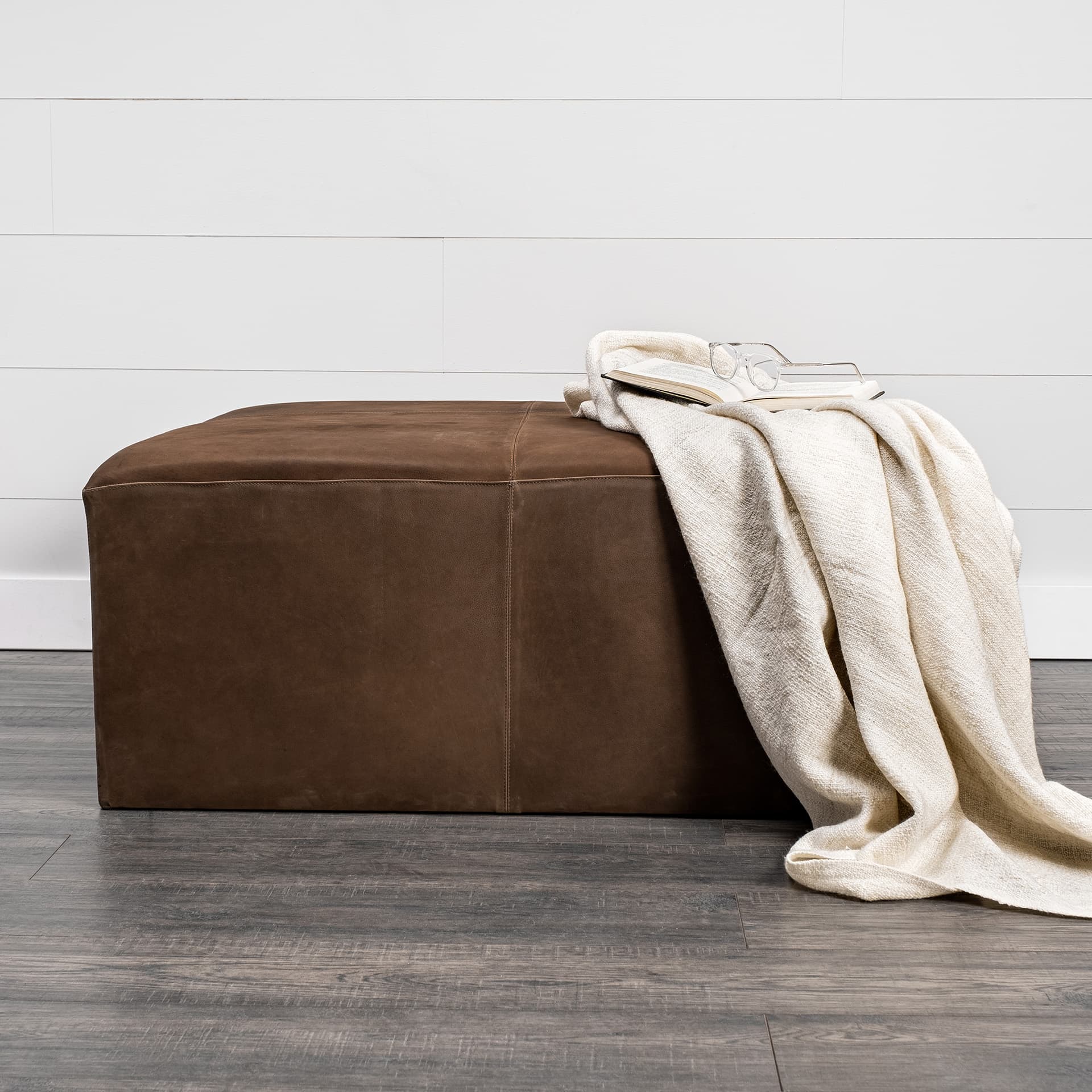 Minara 36" Square Brown Leather Wrapped w/Wood Base Ottoman — in a styled room